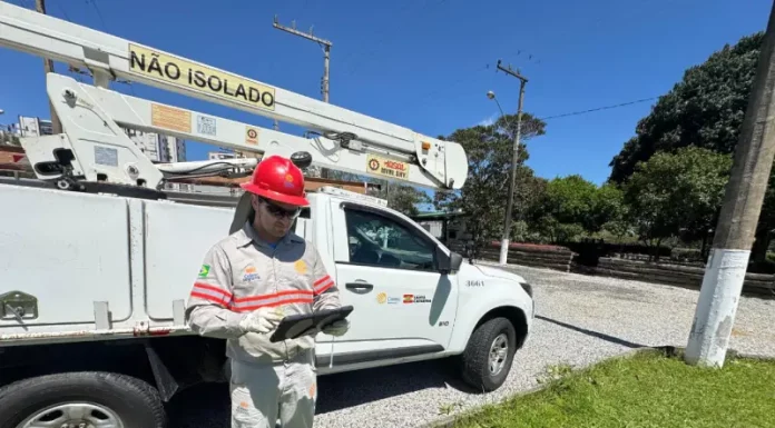 Funcionário da Celesc utilizando tablet em frente a veículo de atendimento emergencial, ilustrando o uso da internet Starlink para agilizar operações em campo.