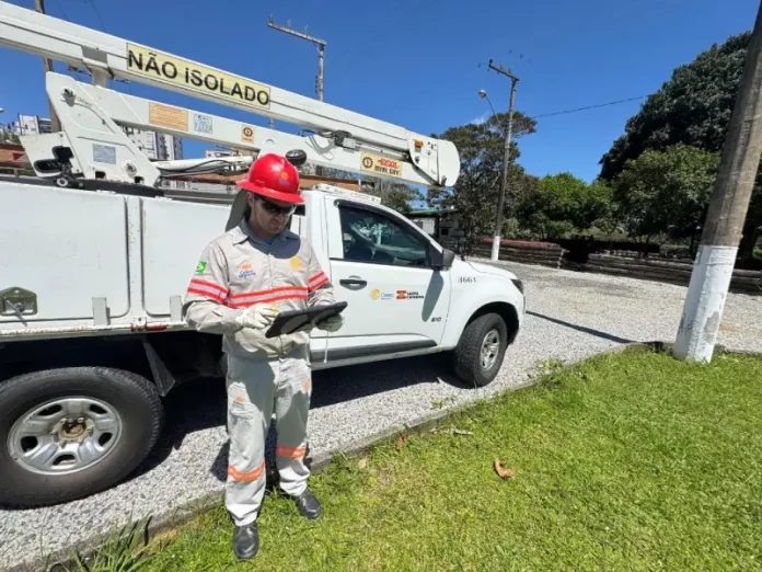 Funcionário da Celesc utilizando tablet em frente a veículo de atendimento emergencial, ilustrando o uso da internet Starlink para agilizar operações em campo.