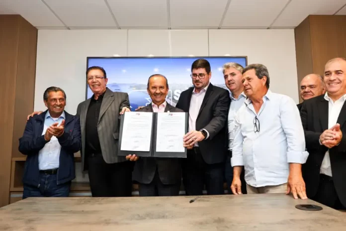 Foto dos líderes políticos de São José e de Santa Catarina durante o lançamento dos editais de construção da Beira-Mar de Barreiros, segurando a pasta oficial que marca o início da obra.
