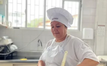 Maise Ferreira de Jesus, cozinheira da rede municipal de Florianópolis, prepara uma refeição em panela sobre o fogão, ilustrando seu trabalho na alimentação escolar