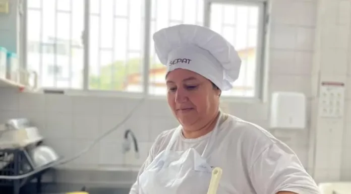 Maise Ferreira de Jesus, cozinheira da rede municipal de Florianópolis, prepara uma refeição em panela sobre o fogão, ilustrando seu trabalho na alimentação escolar