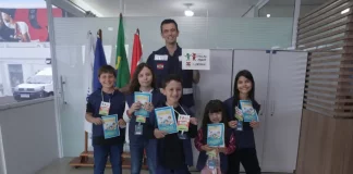 Crianças posam com o supervisor Silvio Dias, da Regional do Imetro de Tubarão, segurando cartilhas do Projeto Fiscal Mirim, destacando a iniciativa de ensino sobre fiscalização e metrologia.