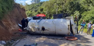 Caminhão capotado enquanto equipe de bombeiros realiza resgate do motorista preso nas ferragens.