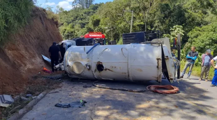 Caminhão capotado enquanto equipe de bombeiros realiza resgate do motorista preso nas ferragens.