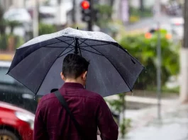 Frente fria mantém chuva intensa e temporais isolados em Santa Catarina Homem caminhando na chuva com guarda-chuva, mostrando os efeitos da frente fria que provoca chuva intensa e temporais isolados em Santa Catarina.