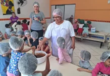 O sonho de Stela: ser cozinheira de um grande público Cozinheira Stela na cozinha do NEIM Mateus de Barros, auxiliando crianças no preparo da massa de bolo, em atividade educativa e prática de alimentação saudável.