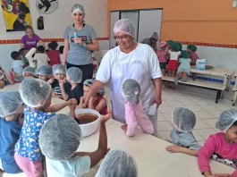 O sonho de Stela: ser cozinheira de um grande público Cozinheira Stela na cozinha do NEIM Mateus de Barros, auxiliando crianças no preparo da massa de bolo, em atividade educativa e prática de alimentação saudável.