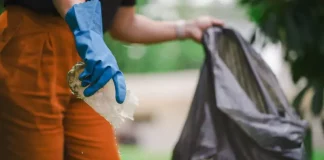 Homem recolhendo um pedaço de plástico com água parada para eliminar possíveis criadouros do mosquito Aedes aegypti e focos de dengue.