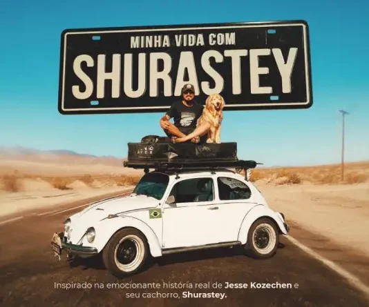 Cena promocional do filme “Minha Vida com Shurastey”, mostrando um homem e seu cachorro sobre um fusca branco em uma estrada desértica, sob uma placa com o título do longa. A imagem é usada para divulgar a produção inspirada na história real de Jesse Kozechen e seu cão Shurastey.