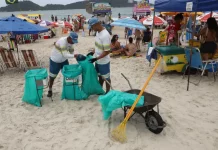 Comcap reabre chamada para prova prática do concurso de gari temporário Garis coletando lixo na praia durante o verão, ilustrando a contratação temporária da Comcap.