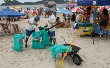 Florianópolis convoca 371 temporários para reforço na limpeza do verão Garis coletando lixo na praia durante o verão, ilustrando a contratação temporária da Comcap para reforço na limpeza