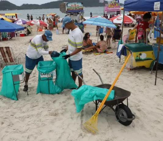 Comcap reabre chamada para prova prática do concurso de gari temporário Garis coletando lixo na praia durante o verão, ilustrando a contratação temporária da Comcap.