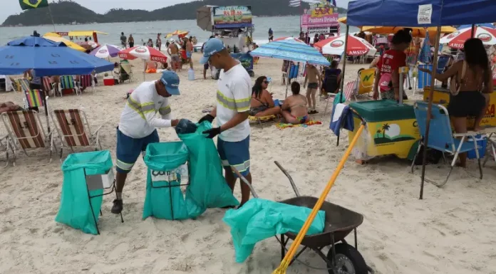 Comcap reabre chamada para prova prática do concurso de gari temporário Garis coletando lixo na praia durante o verão, ilustrando a contratação temporária da Comcap.
