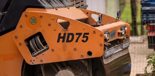 Biguaçu garante R$ 20 milhões para pavimentação na cidade Rolo compressor realizando pavimentação de rua em Biguaçu, representando obras de infraestrutura da cidade.