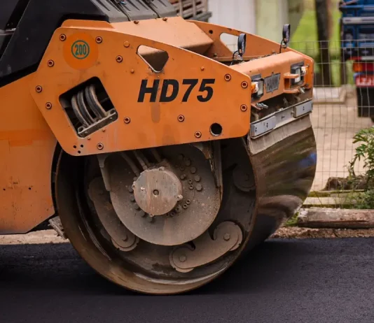 Biguaçu garante R$ 20 milhões para pavimentação na cidade Rolo compressor realizando pavimentação de rua em Biguaçu, representando obras de infraestrutura da cidade.