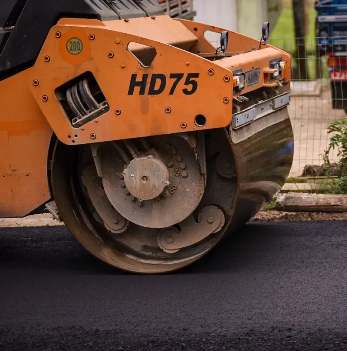 Rolo compressor realizando pavimentação de rua em Biguaçu, representando obras de infraestrutura da cidade.