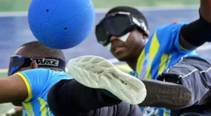 Fesporte lança edital de R$ 8 milhões destinado ao paradesporto catarinense Dois atletas com deficiência visual disputam uma partida de goalball, esporte paralímpico. Ambos usam vendas nos olhos e uniformes esportivos. Um deles está em movimento defensivo, tentando bloquear uma bola azul com o corpo. A imagem representa o dinamismo e a inclusão no paradesporto, contexto do edital lançado pela Fesporte para apoiar projetos esportivos voltados a pessoas com deficiência em Santa Catarina.