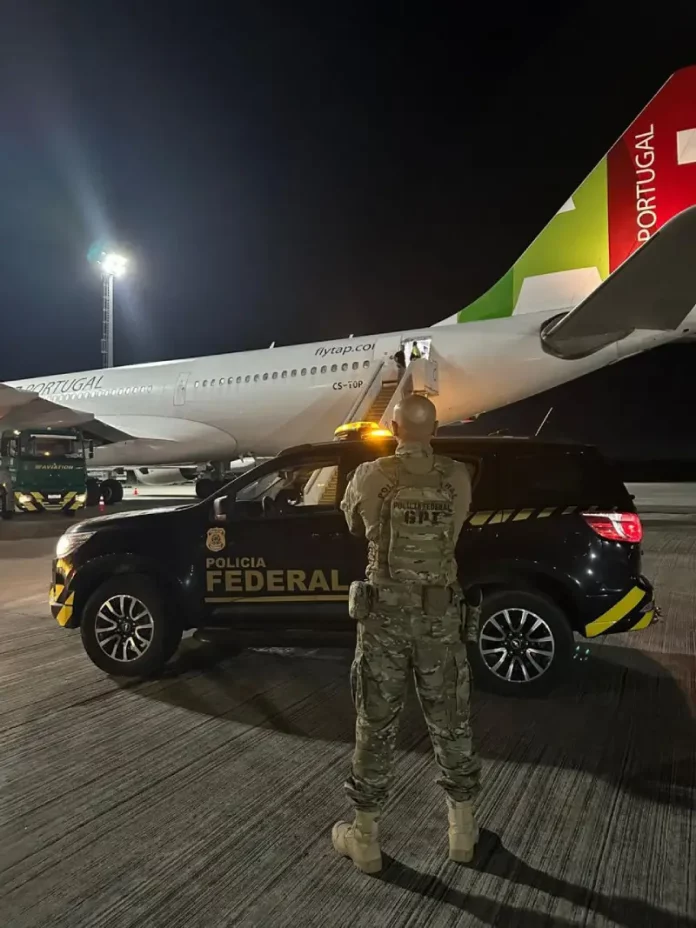 Agente da Polícia Federal acompanha, na pista do Aeroporto Internacional de Florianópolis, o embarque de cidadão finlandês em voo internacional durante operação de expulsão do país.