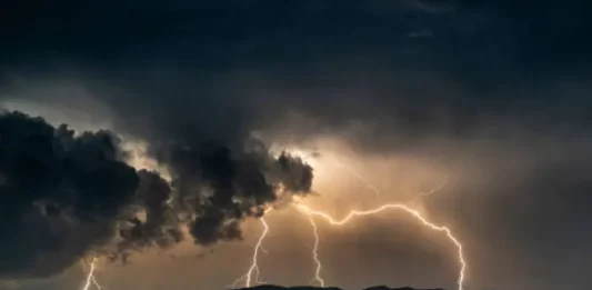 Imagem ilustrativa da frente fria: nuvens escuras e carregadas com raios sobre a cidade, representando a instabilidade e os temporais previstos para Santa Catarina.