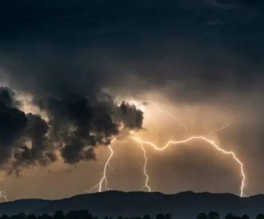 Imagem ilustrativa da frente fria: nuvens escuras e carregadas com raios sobre a cidade, representando a instabilidade e os temporais previstos para Santa Catarina.