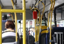 Foto interna de um ônibus do transporte público de Florianópolis, com foco na catraca e uma senhora sentada na frente.