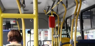 Foto interna de um ônibus do transporte público de Florianópolis, com foco na catraca e uma senhora sentada na frente.