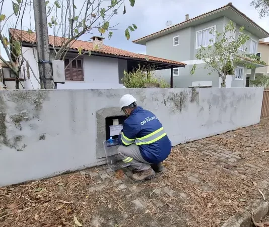 Técnico da Águas de Palhoça realiza leitura e inspeção em hidrômetro residencial, representando as atividades operacionais da concessionária.