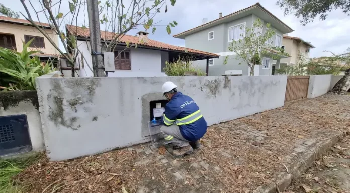Técnico da Águas de Palhoça realiza leitura e inspeção em hidrômetro residencial, representando as atividades operacionais da concessionária.