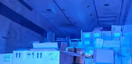 Imagem do interior do baú de um caminhão, mostrando caixas contendo vinhos finos, perfumes e cosméticos, apreendidos pela PRF em operação contra contrabando.