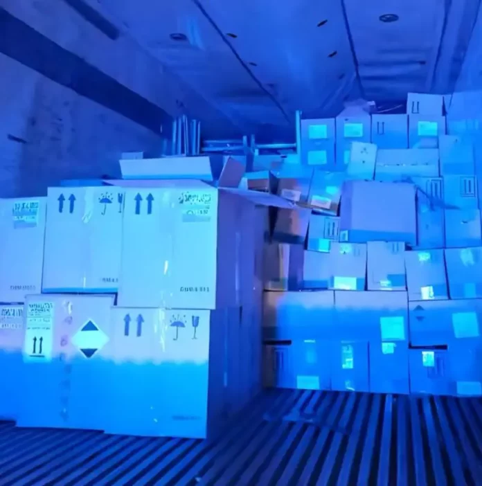 Imagem do interior do baú de um caminhão, mostrando caixas contendo vinhos finos, perfumes e cosméticos, apreendidos pela PRF em operação contra contrabando.