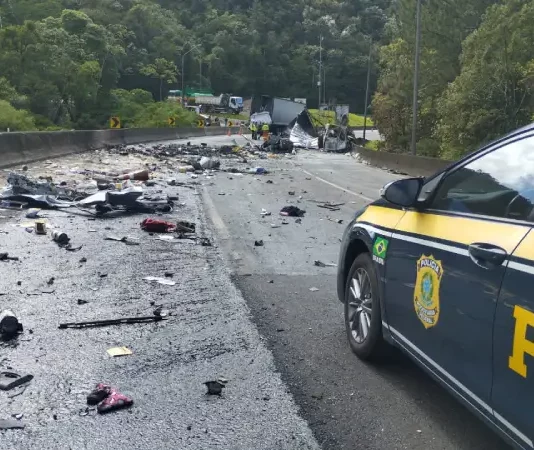 Imagem mostra trecho da BR-376 com destroços espalhados após grave acidente entre van, caminhão e carreta; viatura da Polícia Rodoviária Federal realiza atendimento no local.