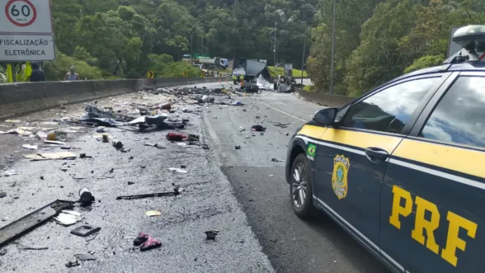 Imagem mostra trecho da BR-376 com destroços espalhados após grave acidente entre van, caminhão e carreta; viatura da Polícia Rodoviária Federal realiza atendimento no local.