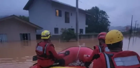 Bombeiros realizam resgates após forte chuva em Luiz Alves Foto mostra bombeiros em um bote inflável durante operação de resgate em área alagada, ilustrando o trabalho das equipes para alcançar moradores isolados pela enchente em Luiz Alves.