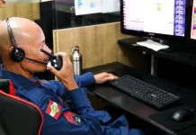 Bombeiro do CBMSC trabalha no computador enquanto fala no rádio para ilustrar o uso de tecnologias que apoiam o atendimento às ocorrências.