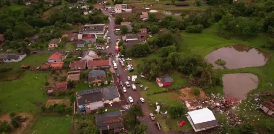Defesa Civil confirma ocorrência de três tornados no Oeste de Santa Catarina Vista aérea mostra parte de Dionísio Cerqueira após a passagem de tornados, com casas destelhadas, destroços espalhados e equipes atuando nas ruas para avaliar os danos e prestar atendimento à população. A imagem ilustra a dimensão dos estragos causados pelo fenômeno climático.