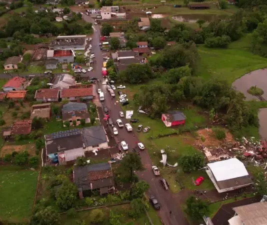 Defesa Civil confirma ocorrência de três tornados no Oeste de Santa Catarina Vista aérea mostra parte de Dionísio Cerqueira após a passagem de tornados, com casas destelhadas, destroços espalhados e equipes atuando nas ruas para avaliar os danos e prestar atendimento à população. A imagem ilustra a dimensão dos estragos causados pelo fenômeno climático.