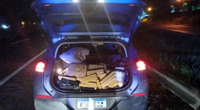 Porta-malas aberto exibindo tabletes de maconha apreendidos, registrados para documentar a ação policial.