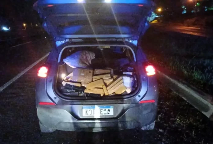 Porta-malas aberto exibindo tabletes de maconha apreendidos, registrados para documentar a ação policial.