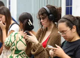 Candidatas conferem informações no celular enquanto aguardam a abertura dos portões para participar do Enem.