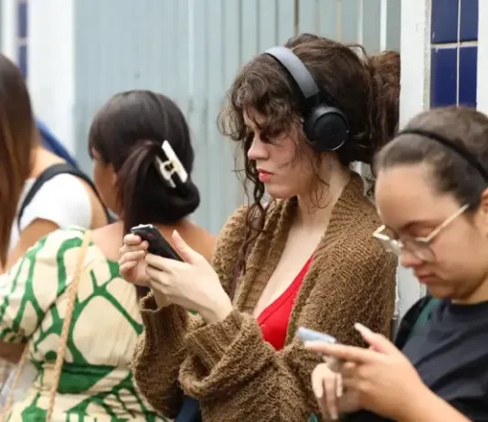 Enem 2025: prazo para pedir reaplicação termina na sexta-feira (21) Candidatas conferem informações no celular enquanto aguardam a abertura dos portões para participar do Enem.