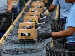 Operários trabalhando em uma linha de montagem de uma indústria catarinense, ilustrando o avanço da produção e o crescimento econômico acima da média nacional.