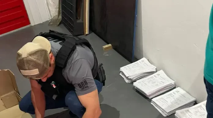 Agentes da Polícia Civil revisam documentos relacionados a investigação de fraudes em processos de transferência de veículos na Ciretran de São José.