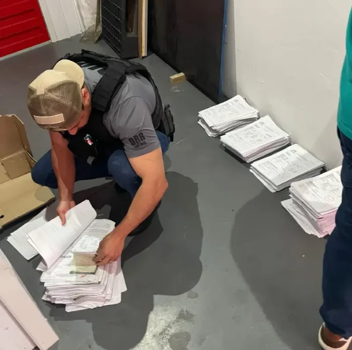 Agentes da Polícia Civil revisam documentos relacionados a investigação de fraudes em processos de transferência de veículos na Ciretran de São José.