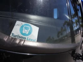 Parabrisa de um veículo de turismo com o Selo Turismo Legal fixado, indicando que o veículo está credenciado para operar conforme as regras da cidade.