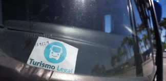 Parabrisa de um veículo de turismo com o Selo Turismo Legal fixado, indicando que o veículo está credenciado para operar conforme as regras da cidade.