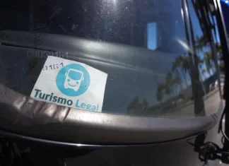 Parabrisa de um veículo de turismo com o Selo Turismo Legal fixado, indicando que o veículo está credenciado para operar conforme as regras da cidade.