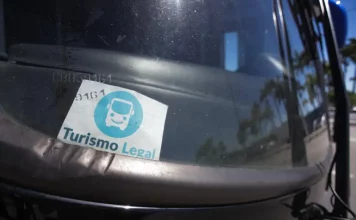 Parabrisa de um veículo de turismo com o Selo Turismo Legal fixado, indicando que o veículo está credenciado para operar conforme as regras da cidade.