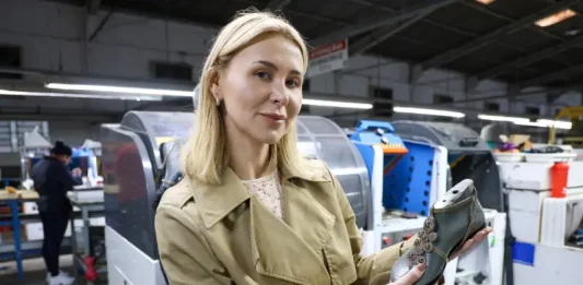 Dia do Empreendedorismo Feminino: SC ultrapassa 1,2 milhão de mulheres empreendedoras A imagem mostra a empresária Suzana Santos em uma fábrica de calçados, segurando um modelo de sapato para representar a presença e a liderança das mulheres no empreendedorismo catarinense.