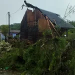 Casa com parte do telhado destruída e árvores caídas após ventos fortes, ilustrando os danos provocados pelo mau tempo em Santa Catarina.