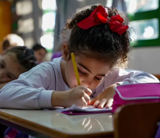 Menina participando de atividades em sala de aula da educação infantil, representando o período em que os estudantes poderão realizar matrículas e transferências escolares.